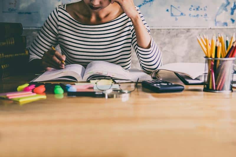 ca student sitting at desk in home studying and reading, doing homework and lesson practice preparing exam to entrance, education concept.